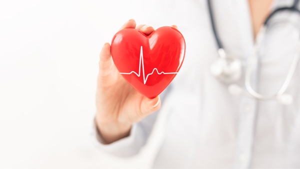 The doctor is holding and showing a red cartoon heart.